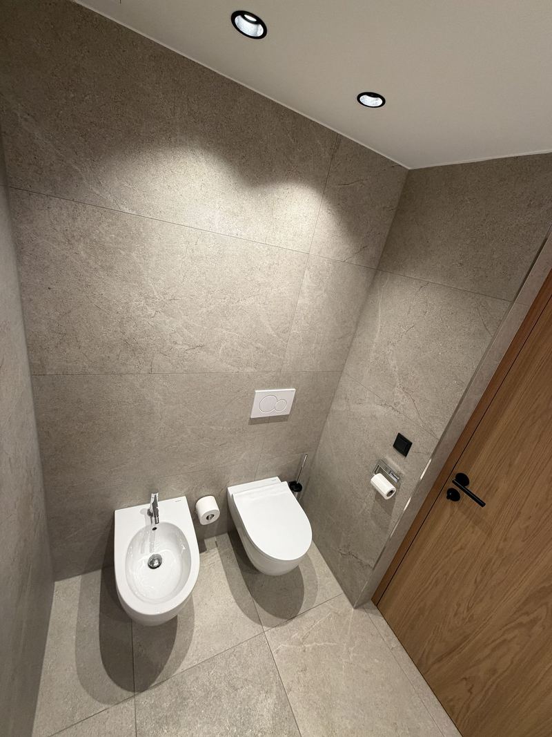 Wandhängendes WC und Bidet vor großformatigen Fliesen